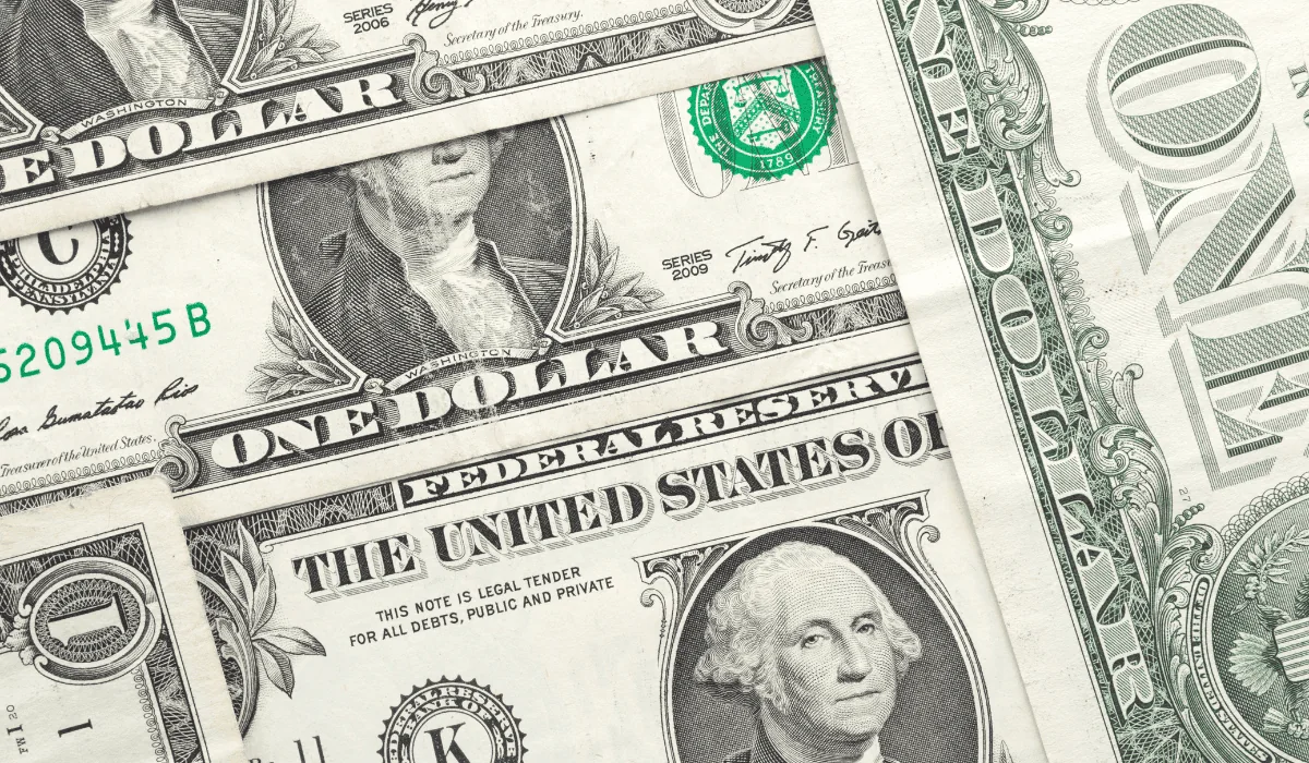 Personas observan un letrero con la cotización del dólar en Colombia mientras la divisa cae por debajo de $3.100