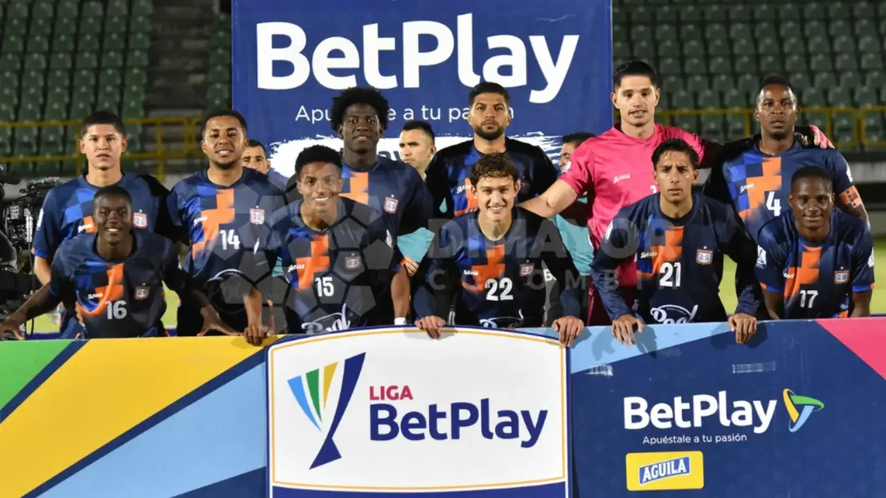 Escudo del Boyacá Chicó y jugadores en la cancha durante un partido del fútbol colombiano