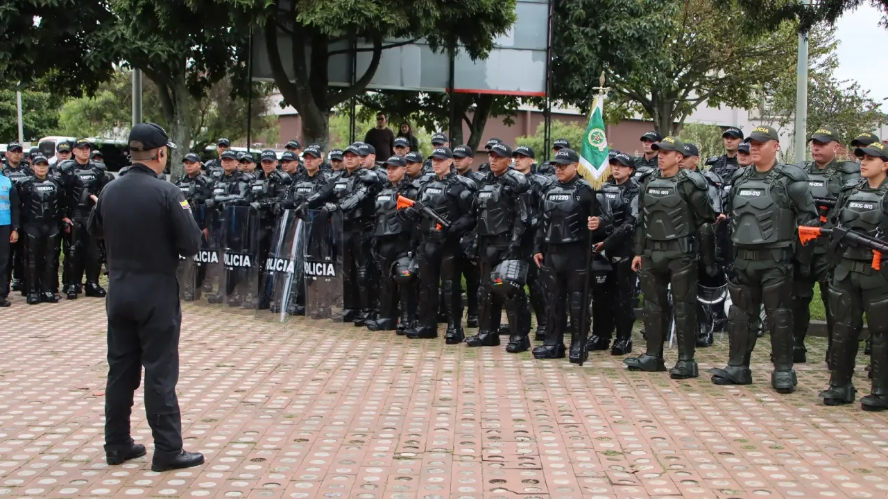 Uniformados de la Policía Nacional de Colombia equipados para el control de disturbios en formación sobre una vía.