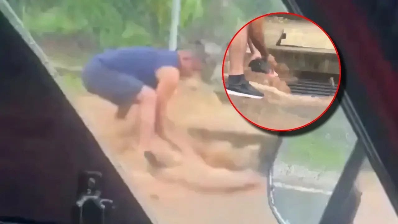 Transeúntes realizan labores de rescate a una niña atrapada en una corriente de agua en una calle de Sonsonate, El Salvador.